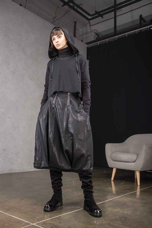 Person wearing a dark outfit with a hood in an indoor setting
