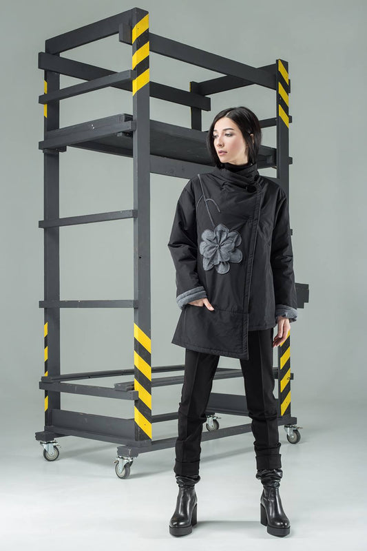Person standing next to a large black metal ladder with yellow stripes on a gray background
