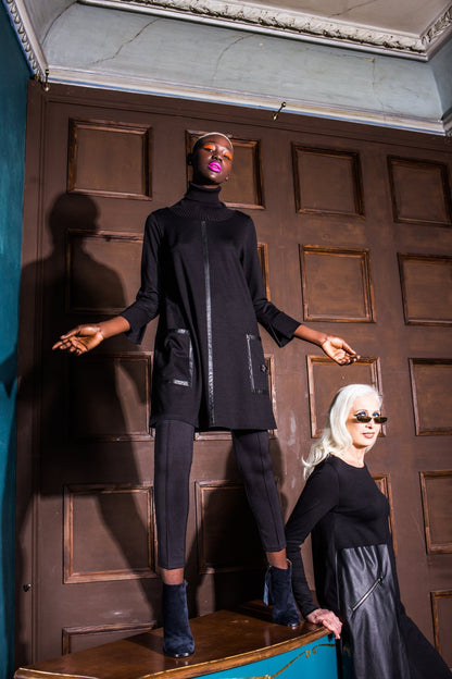 Two women in black outfits standing in a room with wooden paneling. Japanese fabric 