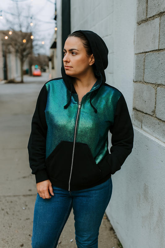 Woman wearing a black and teal jacket standing against a wall.