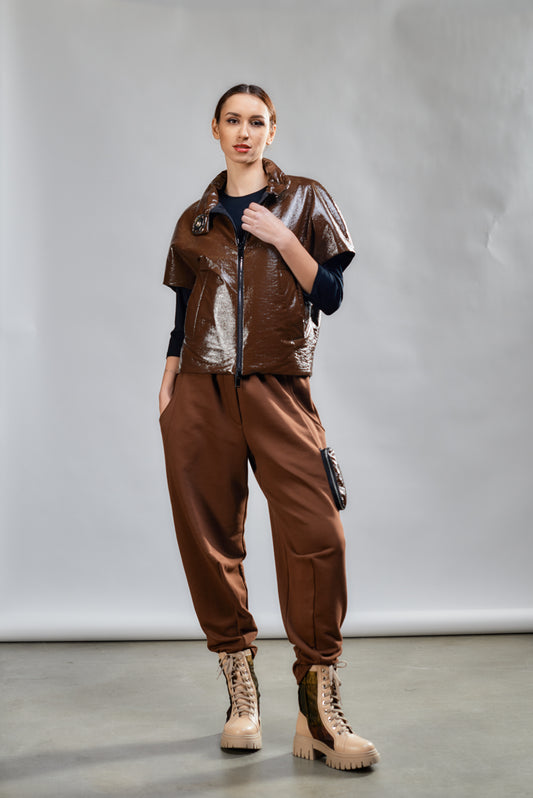 Person wearing a brown outfit with a metallic vest against a plain background
