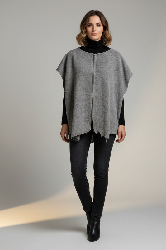 Woman wearing a gray poncho perforated leather  over a black outfit on a neutral background