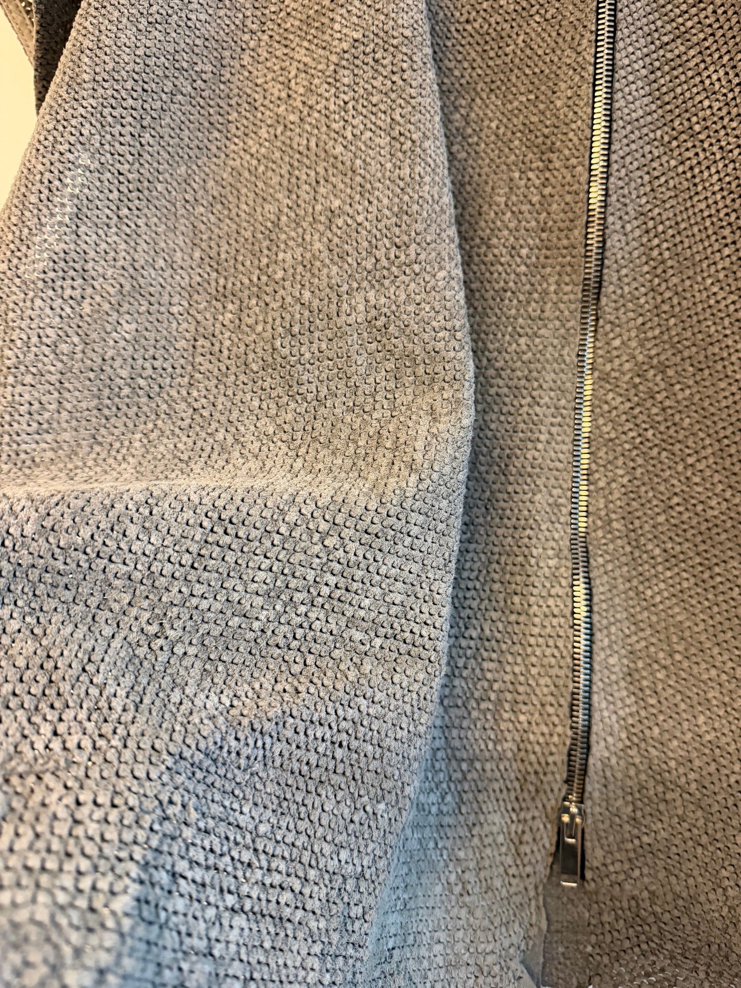 Close-up of a textured real lamb leather with a zipper running along the top edge.